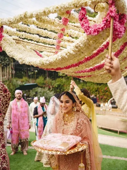 The bride's entry under a beautiful 'phoolon ki chaadar' made of fresh jasmine and pink flowers. A timeless and emotional moment.