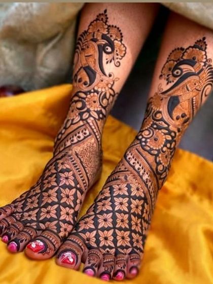 A bold and artistic foot design featuring stylized peacock motifs that curve gracefully along the ankles, paired with a dense floral pattern on the feet.