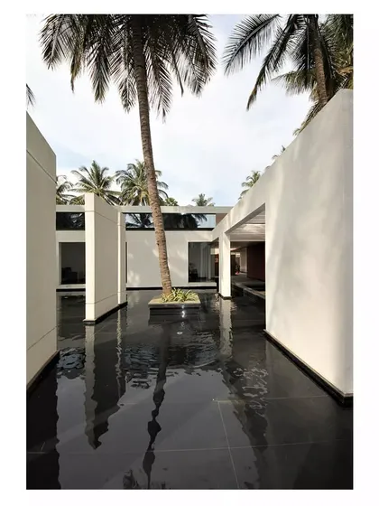 A central water body at the Akriti Experience Centre reflects the surrounding structures and palm trees. This creates a tranquil, contemplative atmosphere.