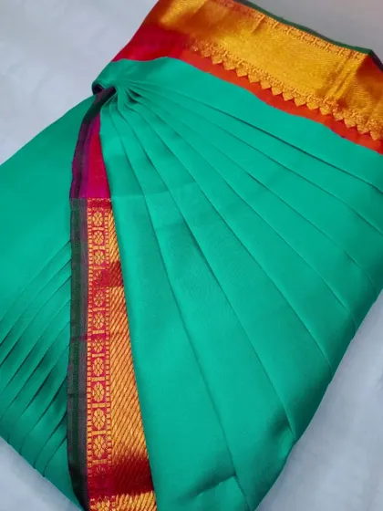 A teal green silk saree with a red and gold border.