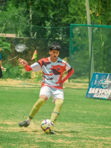 With the Sar Sportz Academy banner in the background, a young athlete showcases his dribbling talent.