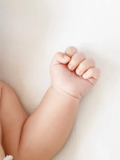 A close up on a sleeping newborn's face, showing their tiny hand curled up. Every detail is worth remembering.