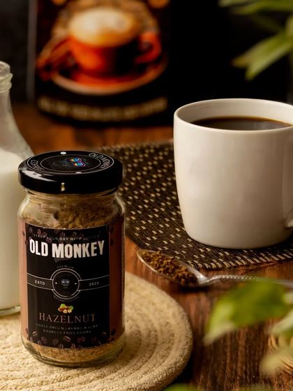 A cozy coffee moment, with a jar of hazelnut coffee, a full mug, and a small bottle of milk. The warm wooden tones and soft lighting create a comfortable and inviting atmosphere.