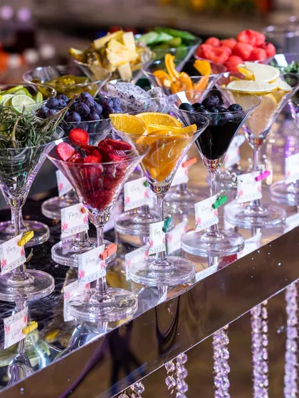 A vibrant and refreshing fruit bar, with a variety of fresh fruits like strawberries, oranges, and grapes served in elegant martini glasses. This is a healthy and visually appealing addition to any event.