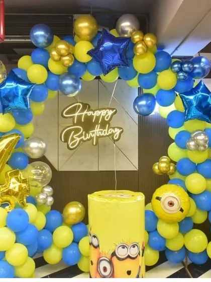 A fun Minions themed birthday party for a 4-year-old. The decor features a balloon arch in classic Minion blue and yellow, with character foils and a marquee number.