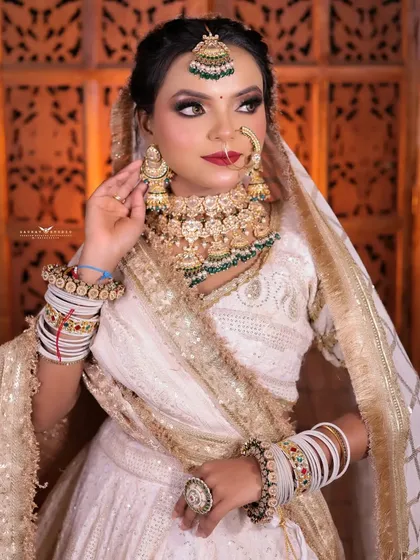 A three-quarter portrait of the bride, her hand adjusting her earring, showcasing the heavy kundan jewelry.
