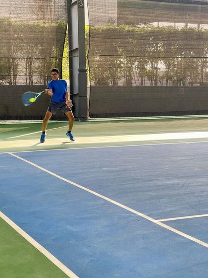A player lunges for a wide forehand, showcasing the athleticism and flexibility we build through our conditioning programs.