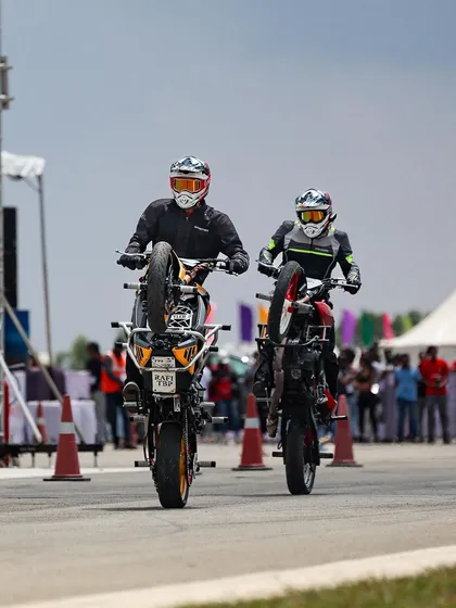 Two stunt riders perform synchronized wheelies, a display of perfect timing and teamwork.