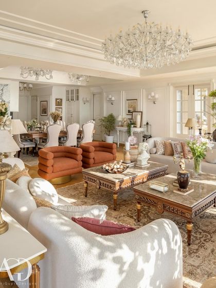 An expansive view of a sun-drenched living and dining area. The open-plan layout is unified by a consistent color palette and classical architectural details, while distinct furniture groupings define each functional zone.