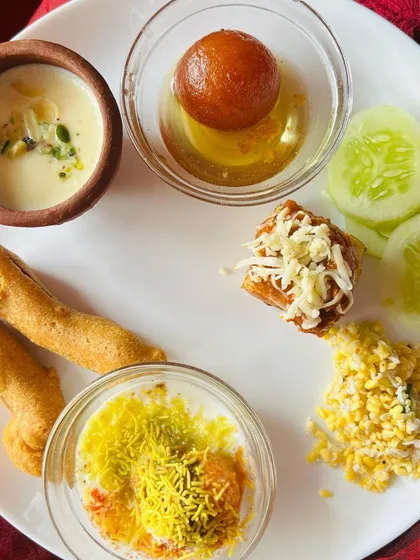 A plate full of my popular starters: Dahi Vada, Mirchi Bajji, a cheesy bite, and Badam Milk. This shows the variety I can offer for a tasting session or an event.