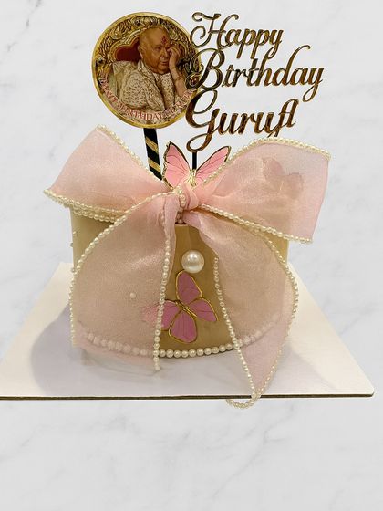 A beautiful and elegant cake to celebrate Guruji's birthday. This design features a delicate pink bow, pearl details, and a custom topper.