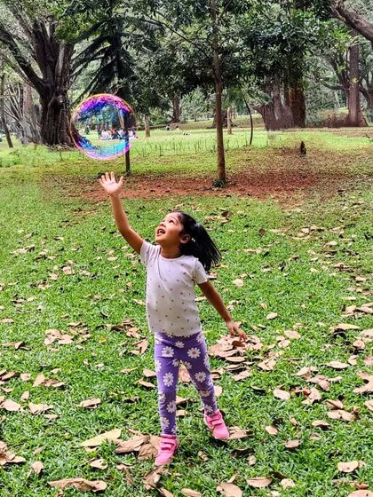 A moment of pure wonder. A young girl reaches for a giant, iridescent bubble, her face filled with awe and delight. It's these simple, magical moments in nature that we cherish the most.