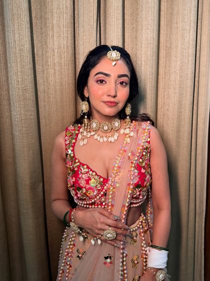 The pop of pink on the eyes adds a playful touch to Neha's Haldi look, tying in with her colorful outfit.