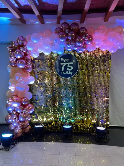 Celebrating 75 years with a dazzling gold sequin wall and a balloon arch in rose gold and pink. This setup is all about glamour and celebration.