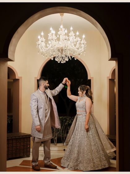 The couple shares a dance under a magnificent crystal chandelier. This elegant shot from their engagement party is full of grace and romance.