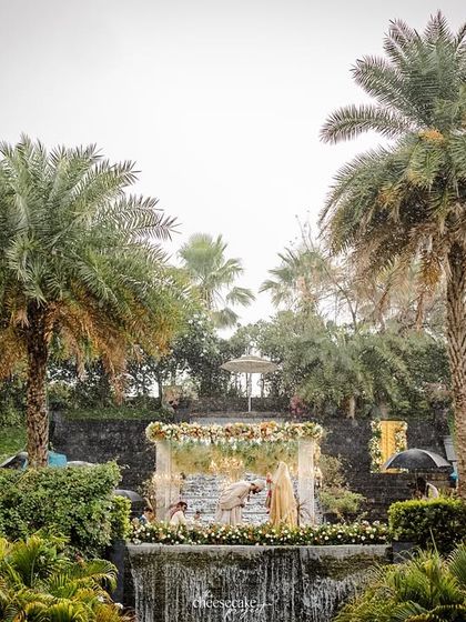 The stunning scale of the wedding venue, with the mandap nestled amongst lush greenery and palm trees.