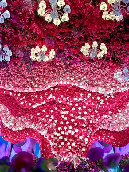 Looking up at the massive floral ceiling installation, dotted with elegant chandeliers. The sheer scale and density of the flowers create an unforgettable spectacle.