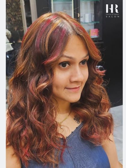A fun and playful look combining a warm brown base with pops of red and blonde highlights, styled into bouncy curls.
