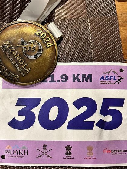 The finisher's medal and race bib from the Rezang La Full Moon Marathon. This is tangible proof of our patient's incredible accomplishment and the successful outcome of her physiotherapy journey.