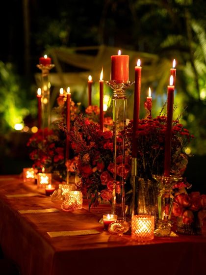 A beautiful table setting for a Christmas dinner, with red candles and festive floral arrangements creating a warm and celebratory mood.