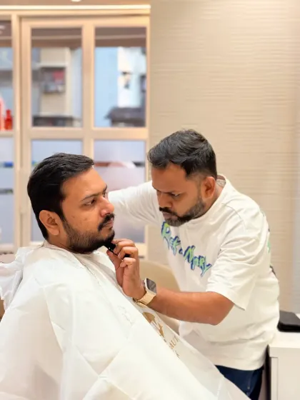 Our client looks on as we meticulously shape his beard. This is a moment of focus and precision, core to our beard grooming and styling services.