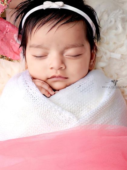 A close-up showing the texture of the white wrap and the baby's tiny hand.