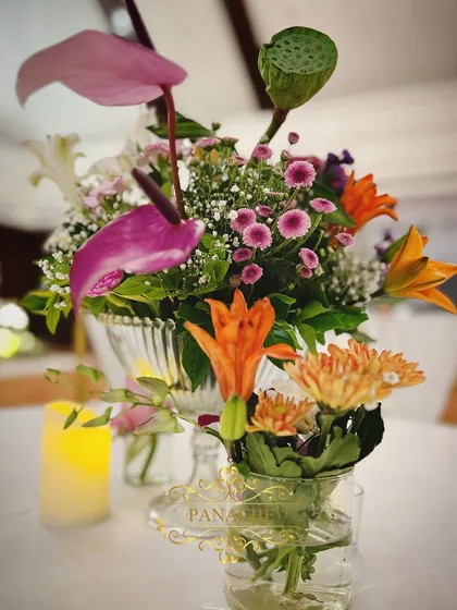 A close-up of the centerpiece, showing the variety of flowers used, including anthuriums and lotus pods.