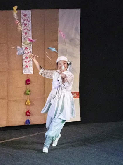 The Korean performer from 'Puppet Fantasy' runs across the stage, trailing butterfly puppets behind her in a beautiful, flowing movement.