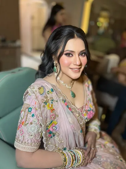 A beautiful engagement bride in a floral embroidered lehenga. The makeup is soft and romantic, with a focus on rosy cheeks and defined eyes.