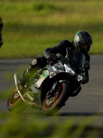 A rider on a Kawasaki Ninja seen through the foliage, focused on the exit of the corner during a session at MMRT.