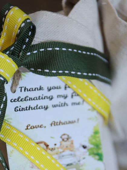 A close-up of the personalized tag on the jungle tote bag, thanking guests for celebrating Atharv's first birthday.
