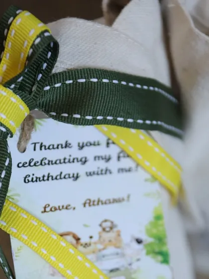 A close-up of the personalized tag on the jungle tote bag, thanking guests for celebrating Atharv's first birthday.