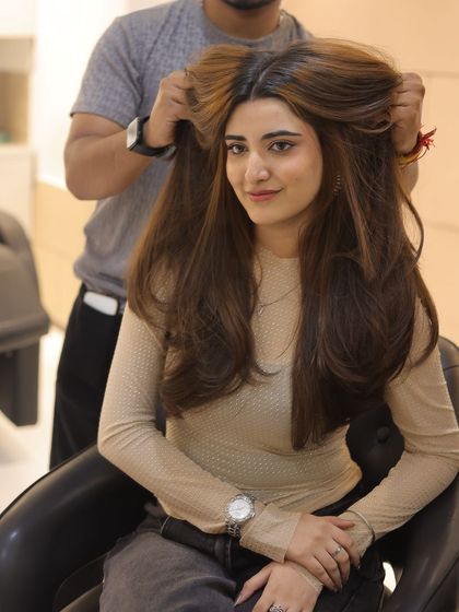 The stylist puts the finishing touches on this voluminous, layered look, ensuring every strand is perfectly in place.