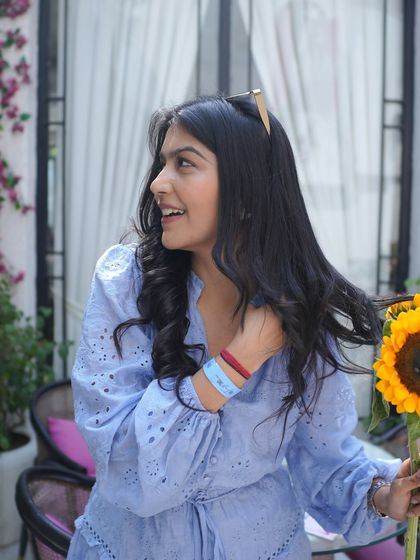 A candid moment in a beautiful sky-blue dress, holding sunflowers. This look is perfect for a sunny day out, a brunch, or a casual date.