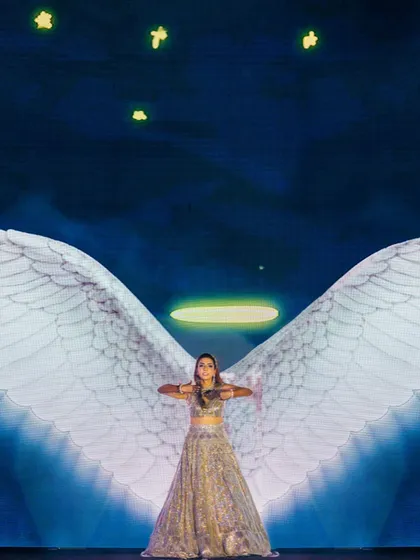A bride's performance with projected angel wings and a halo against a starry night sky. This is an example of how we use technology to create magical, thematic moments.