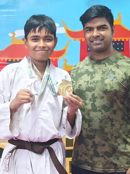 Success in action. Holding up a silver and gold medal from the Open National Karate Championships.