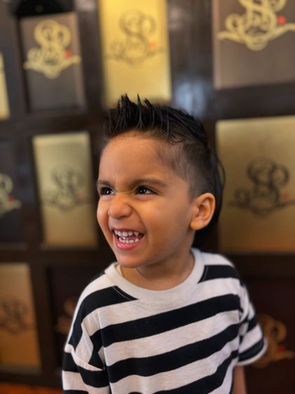 Even our youngest clients leave with the coolest cuts. This little guy is rocking a stylish mohawk with a sharp fade, and his happy expression says it all.