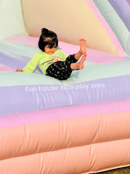 A toddler safely sliding down the colorful ramp of our pastel bounce house.