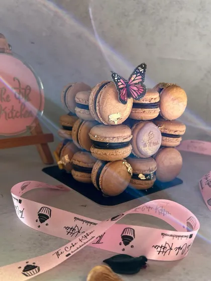 The soft lighting in this shot highlights the delicate butterfly topper and the sheen on the chocolate filling, showing the artistic presentation of the macaron tower.
