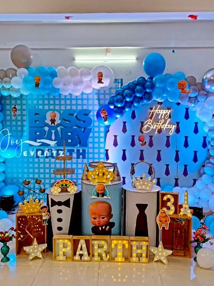 For Parth's 3rd birthday, I designed this Boss Baby setup featuring a circular backdrop with a neon 'Happy Birthday' sign. The theme is carried through with character-themed plinths, a balloon arch, and illuminated marquee letters.
