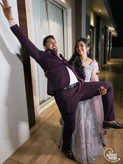 Pure fun and games at the reception! The groom playfully lifts his leg while being held by his smiling bride.