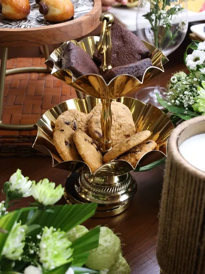 A close-up of our two-tiered scalloped gold stand, filled with brownies and cookies. It’s a classic piece that brings a sense of occasion to any gathering.