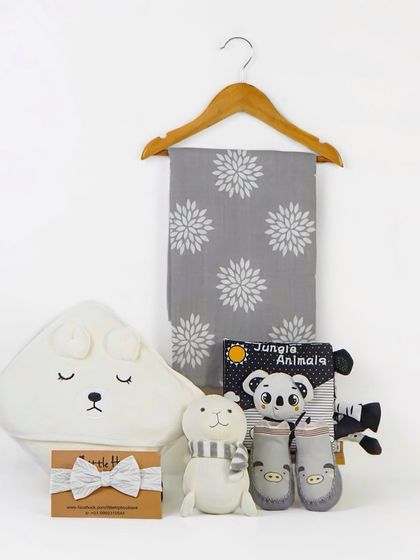 A polar bear themed baby gift set, including a hooded towel, soft toy, and book. The items are arranged to look like a boutique display.