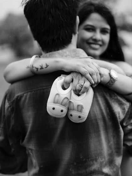 A heartwarming black and white photo focusing on the tiny baby shoes held by the mom-to-be. It’s a simple, powerful image that symbolizes the new life they are about to welcome.