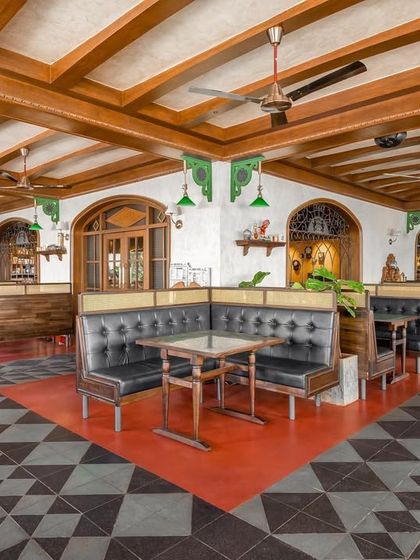 The booth seating at Adda 1522, with its black leather upholstery and surrounding red oxide and patterned floors. This area was designed for comfortable, long conversations, reminiscent of old Bangalore pubs.