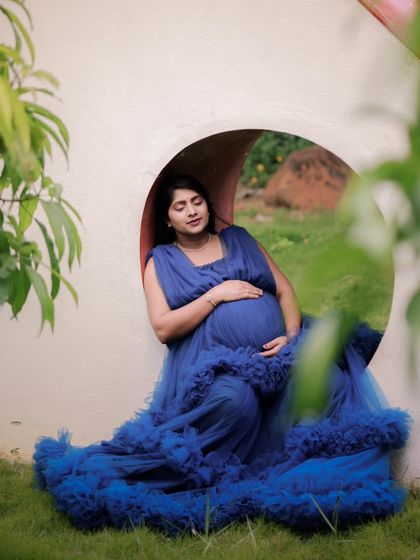 A serene moment captured during a maternity shoot. The client is wearing my royal blue ruffled tulle gown, which is designed to be comfortable and photogenic from every angle.