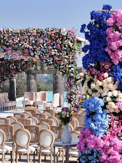A closer view of the floral arrangements and the mandap, highlighting the vibrant color blocking of pink and blue hydrangeas against the soft pastel canopy.