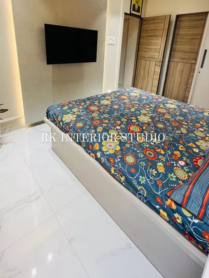 A view of the bedroom showing the wall-mounted TV and the texture-painted wall. This minimalist setup keeps the room feeling open and uncluttered.