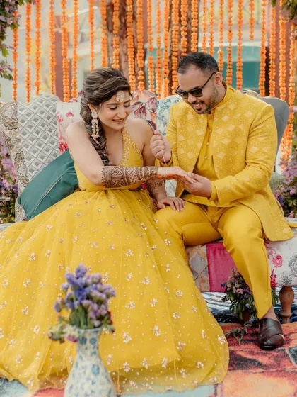 A sweet moment during the Mehendi ceremony, as the groom applies a bit of henna to the bride's hand.