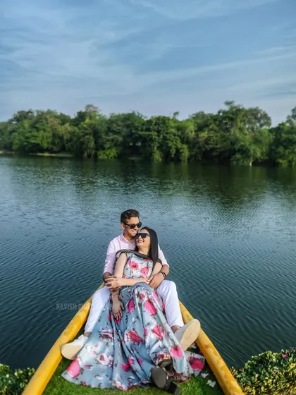 A serene pre-wedding portrait of a couple relaxing in a boat on a calm lake. This shot uses the natural beauty of the water and surrounding greenery to create a peaceful, romantic scene.